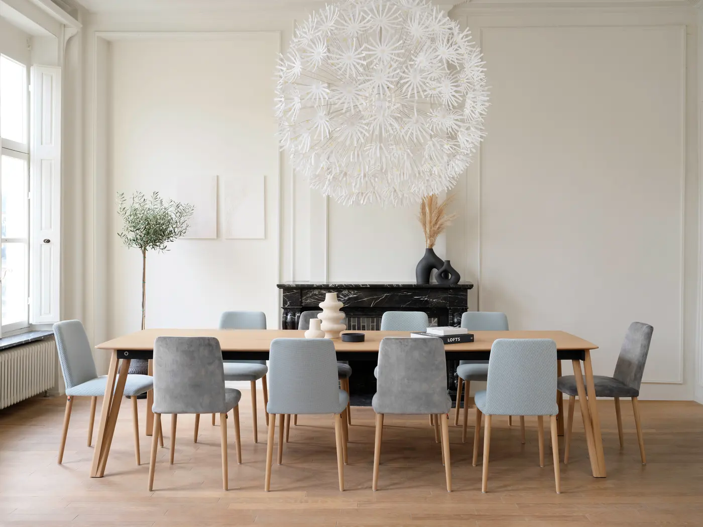 Salle à manger, table en bois et sièges gris, suspension claire.