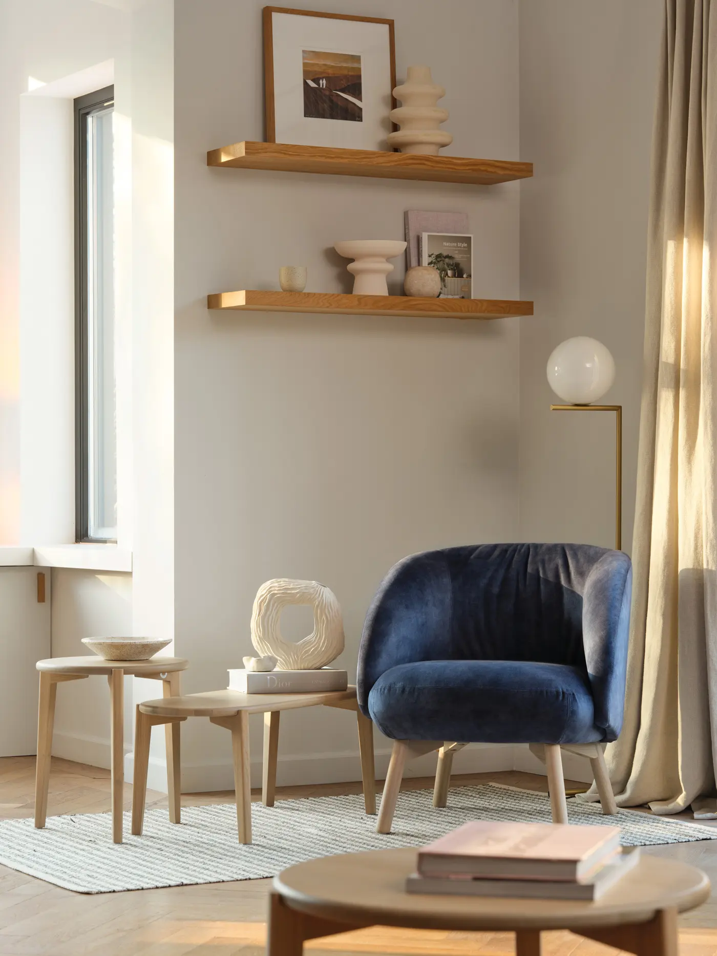 Fauteuil bleu, étagères et lampe dans un coin de séjour.