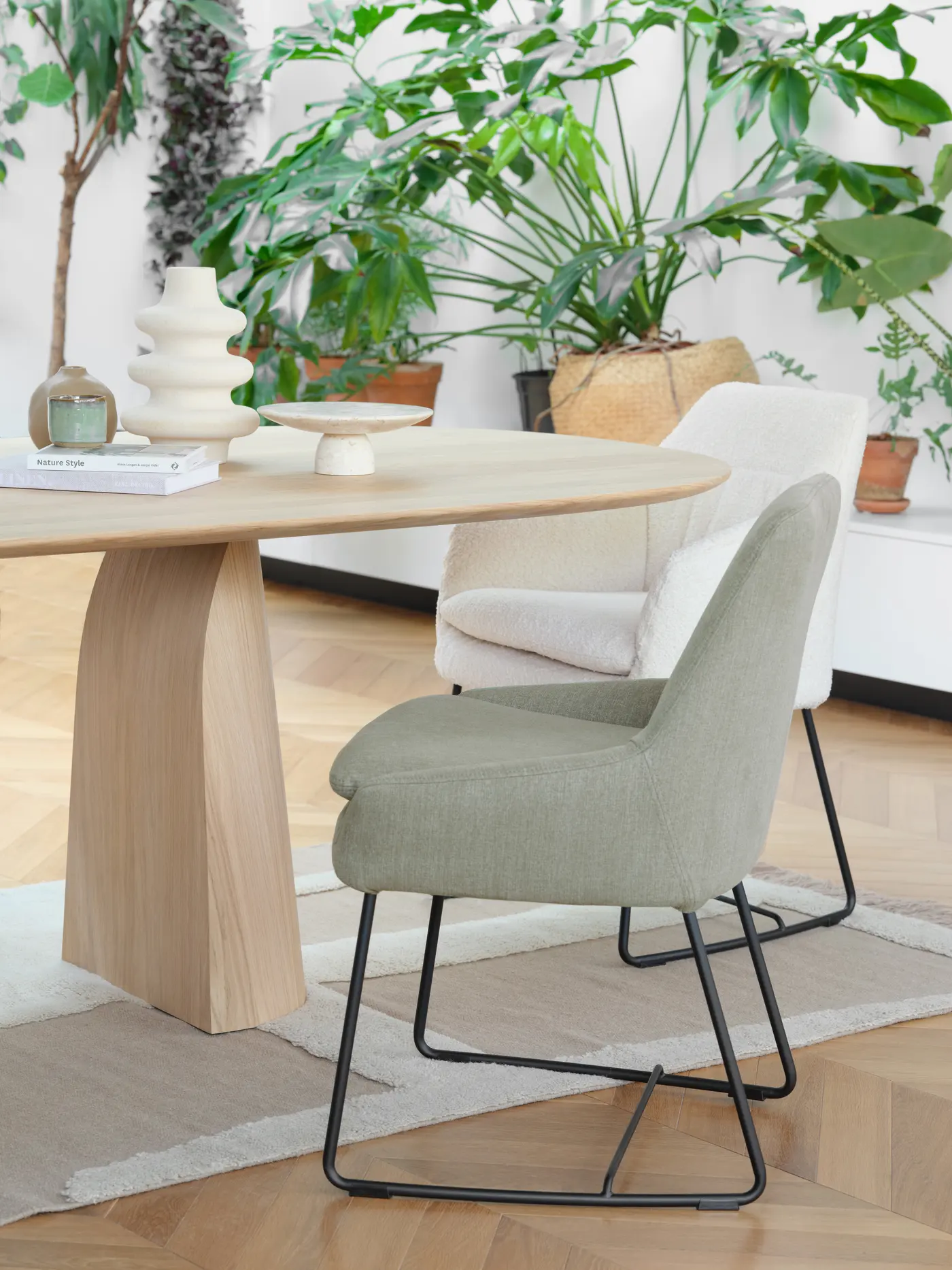Table en bois, plantes et fauteuil clair.