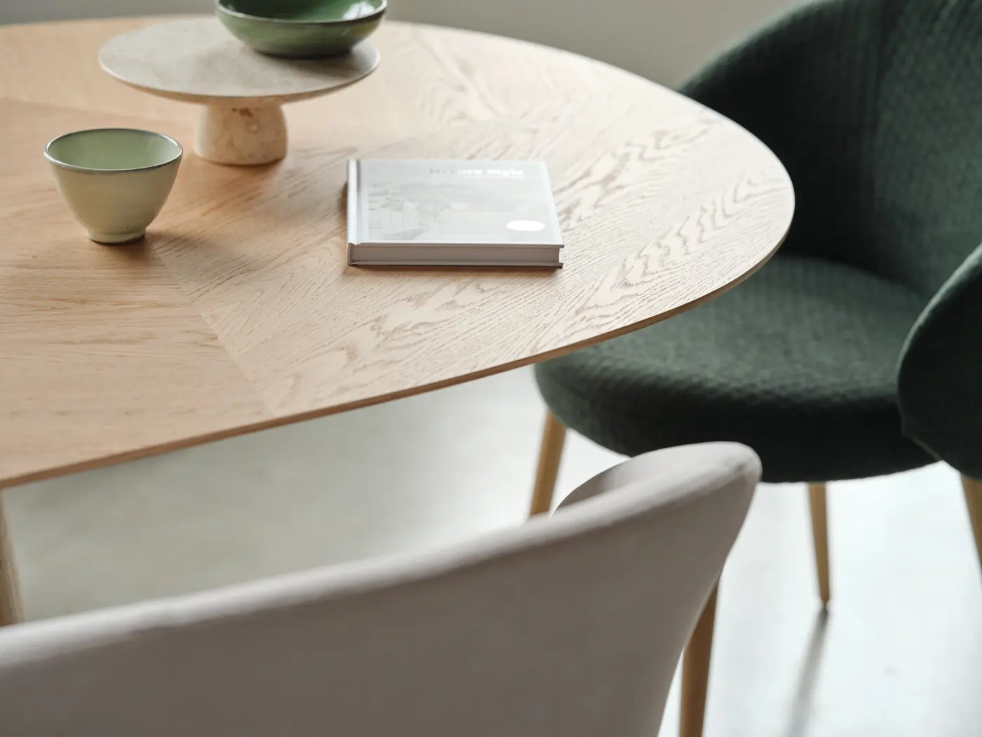 Table ronde en bois clair, céramique et livre.
