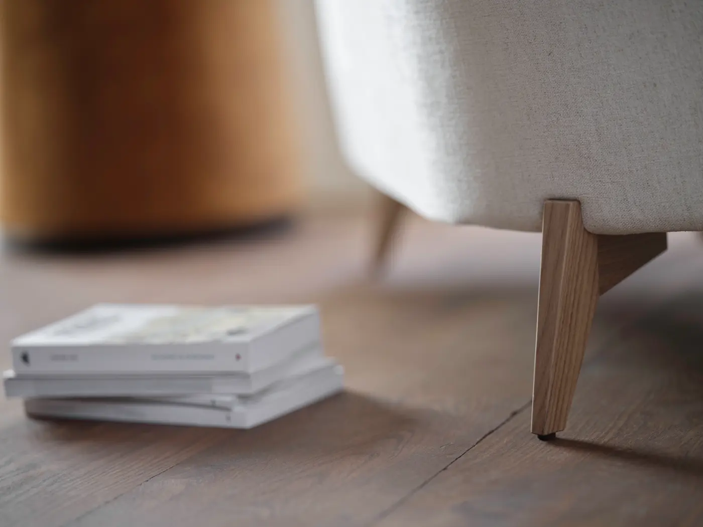 Assise claire, pieds en bois, livres au sol.