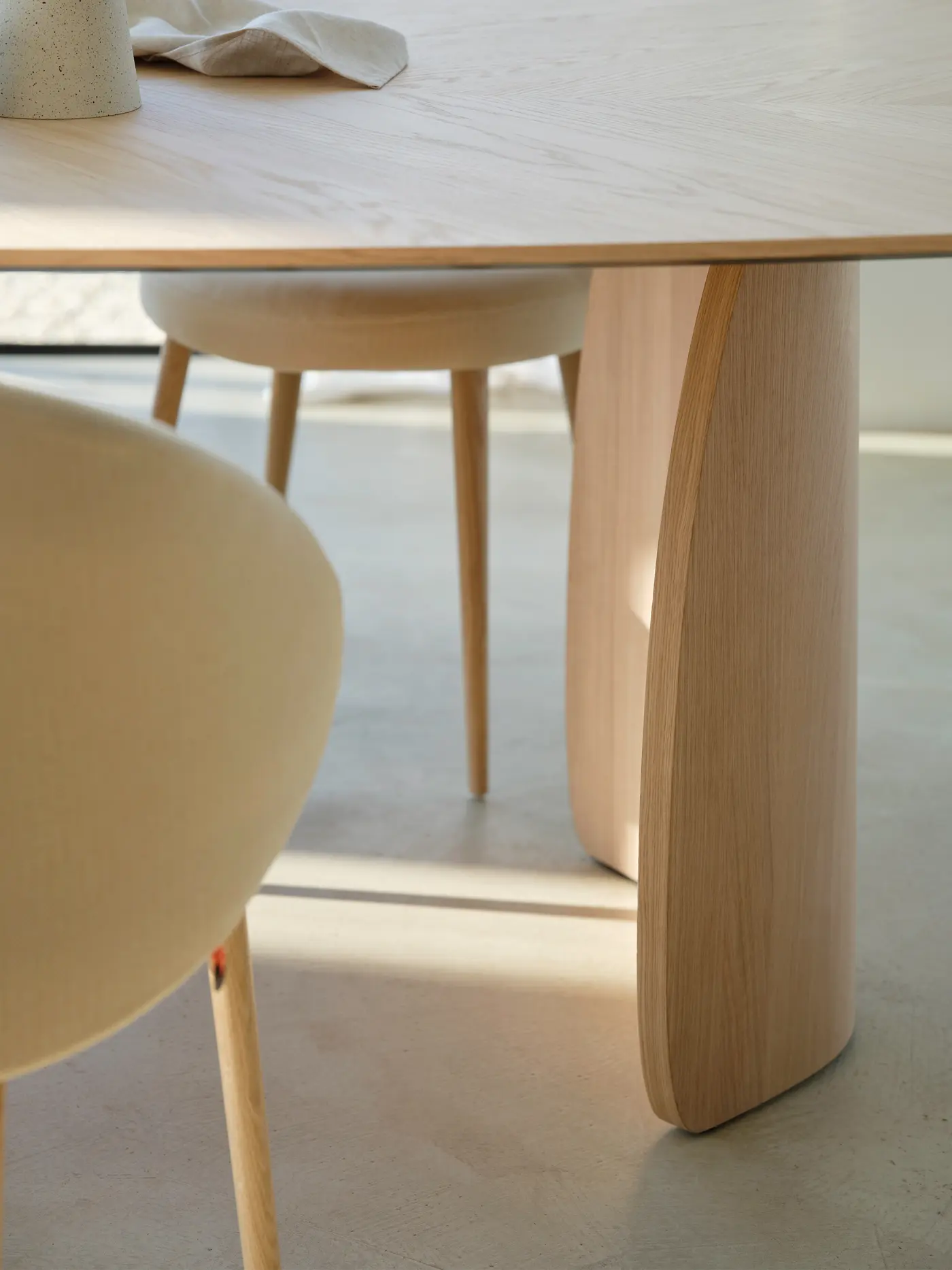 Bord d’un plateau en bois clair et assise arrondie.