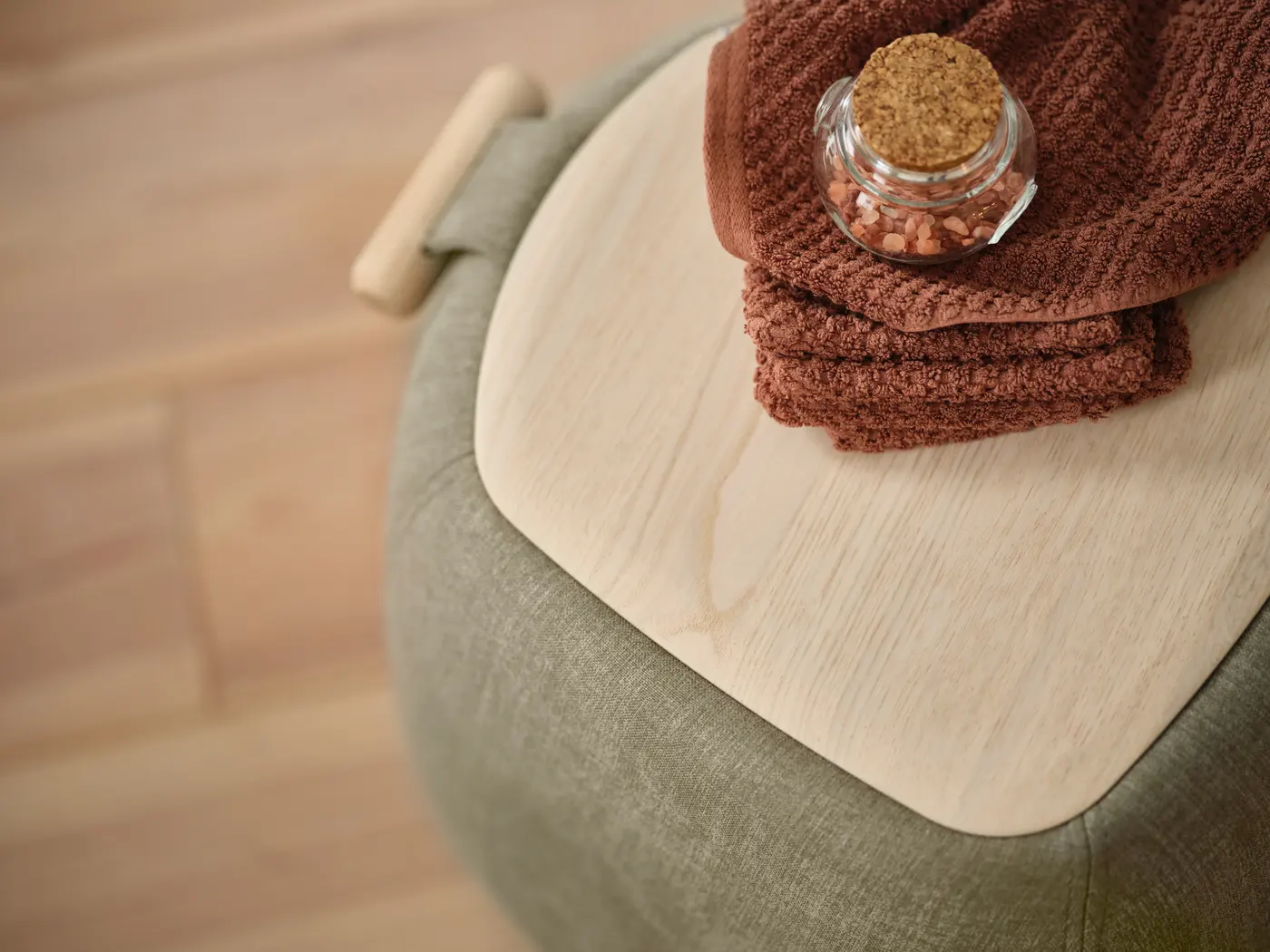 Textile plié sur un plateau en bois, assise verte.