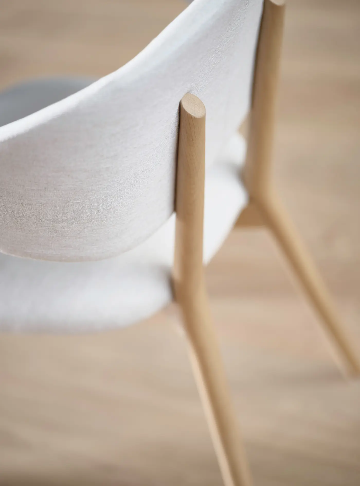 Assise en textile clair et pieds en bois.
